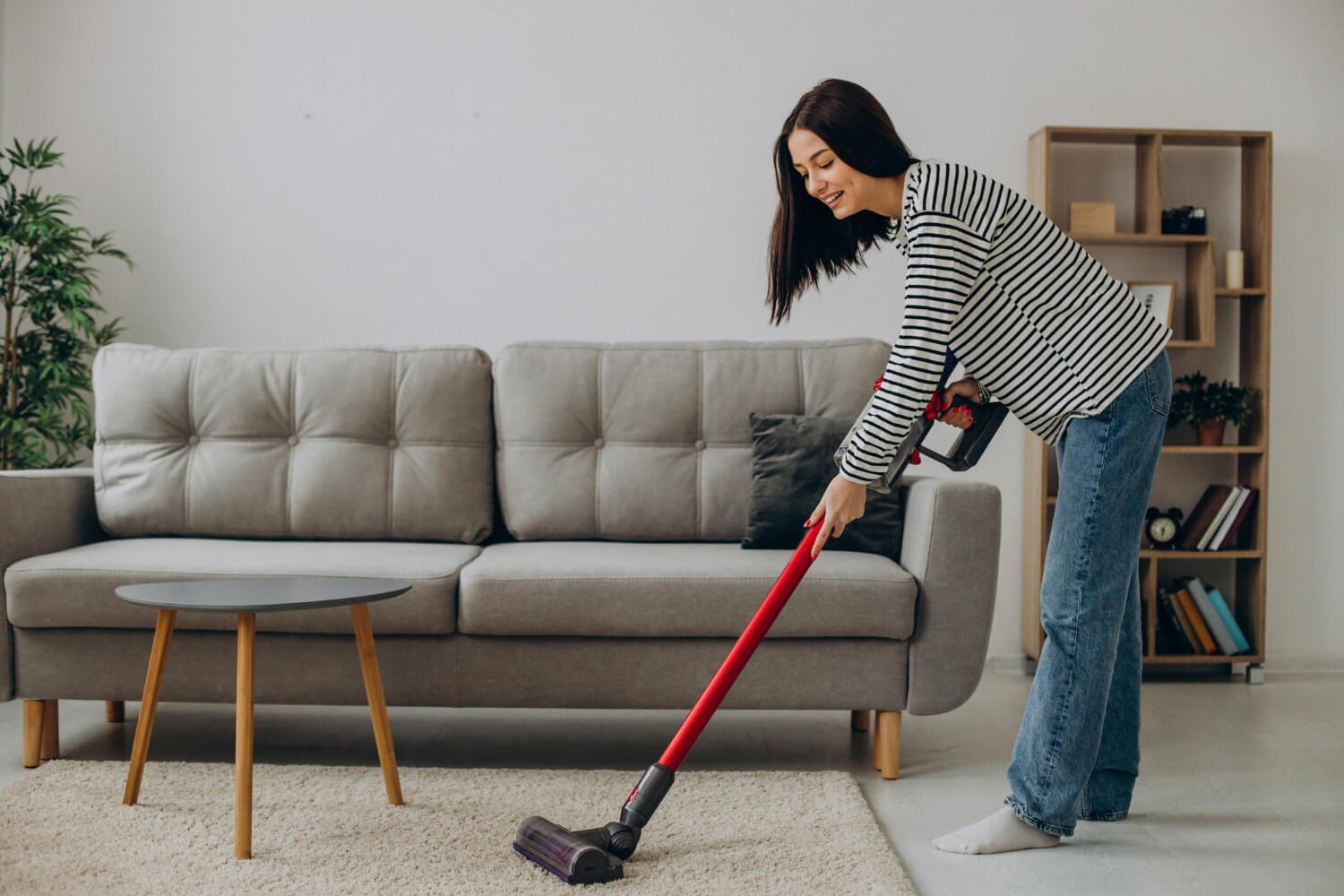 woman vacuuming her carpet in her living room while smilling