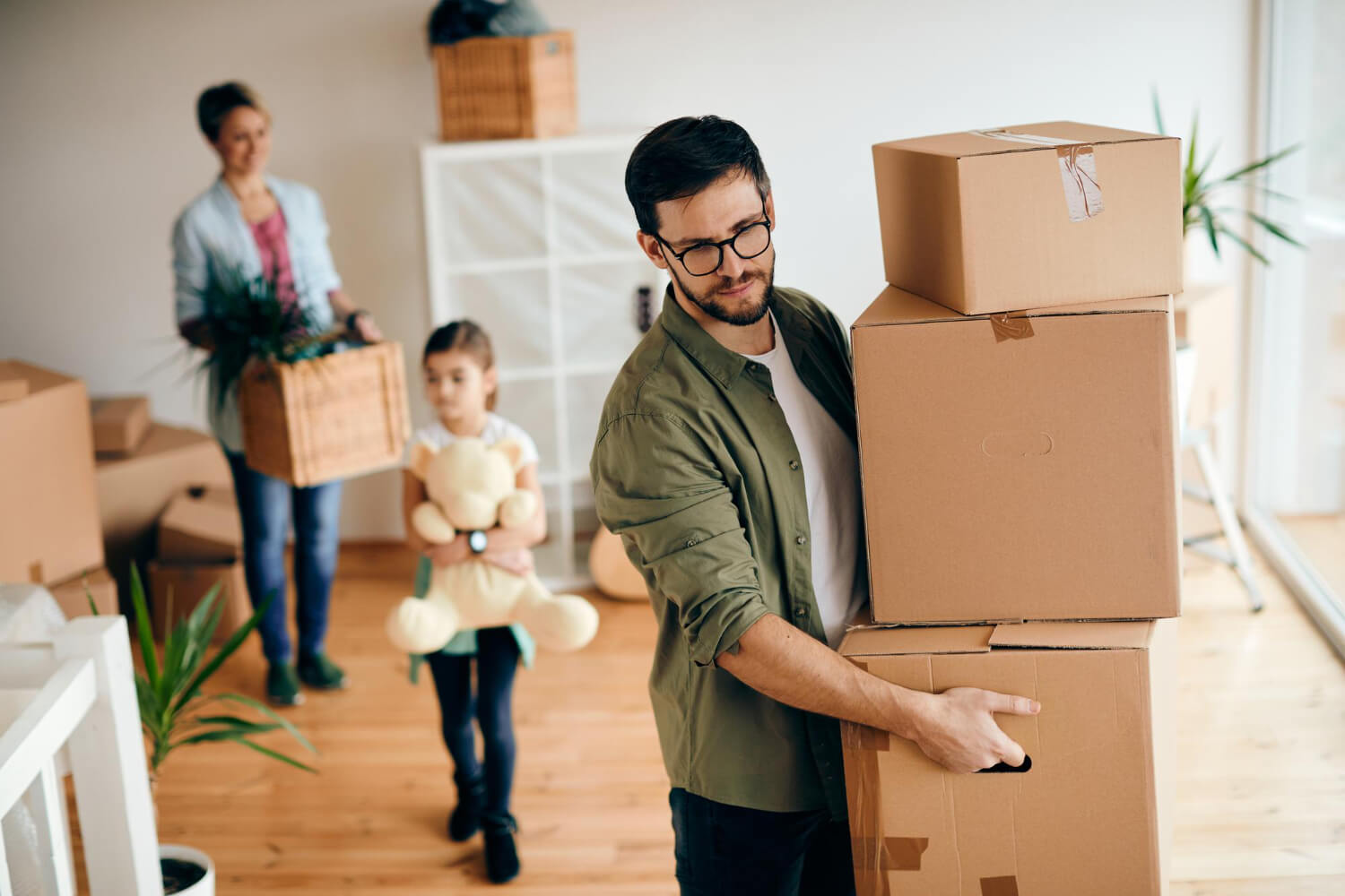 adult man carrying stack carton boxes while moving in his new home with his family