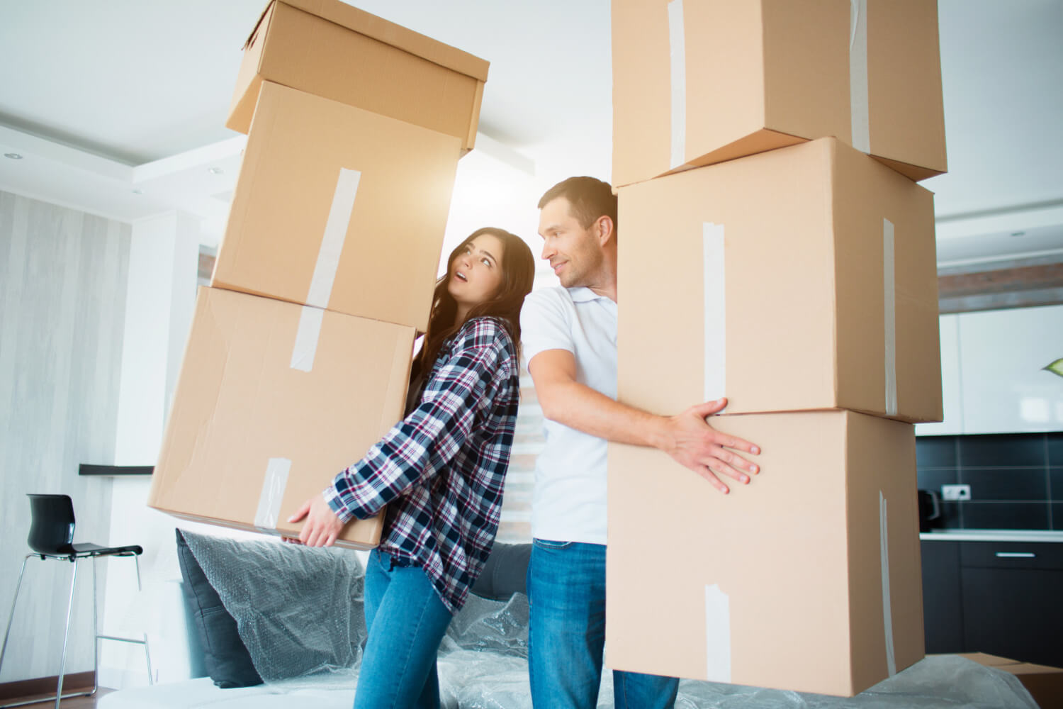 young couple carrying many cardboard boxes one by one while moving in their new home