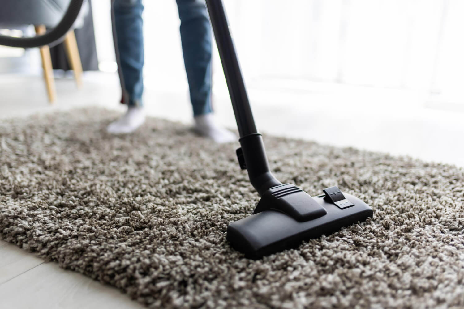 male cleaner cleaning rug with vacuum cleaner