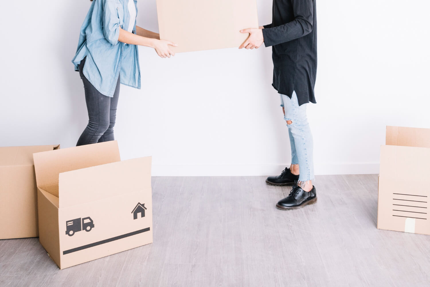 side view of cropped couple holding moving box together for relocation
