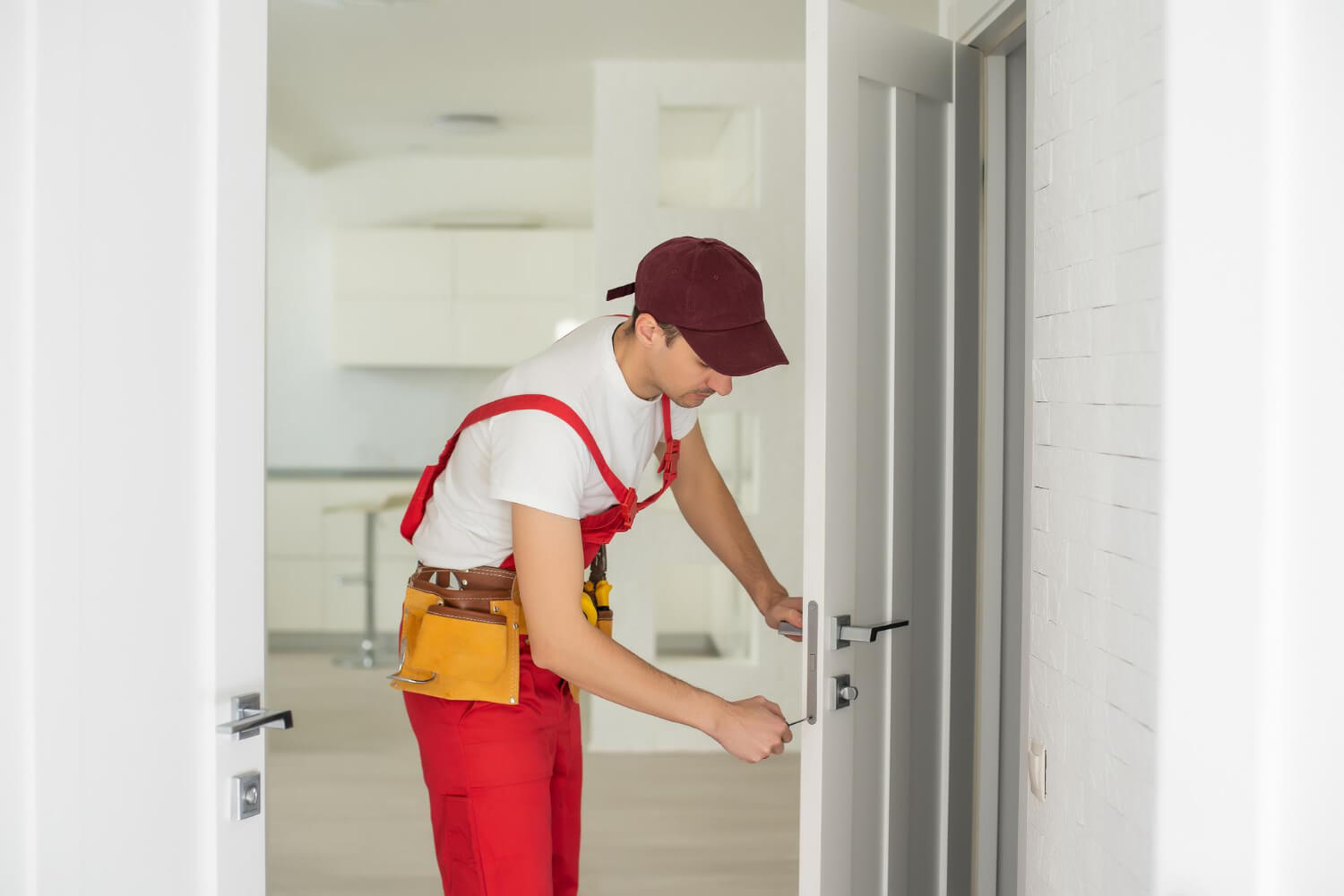 master adjusts fittings door handyman in red uniform