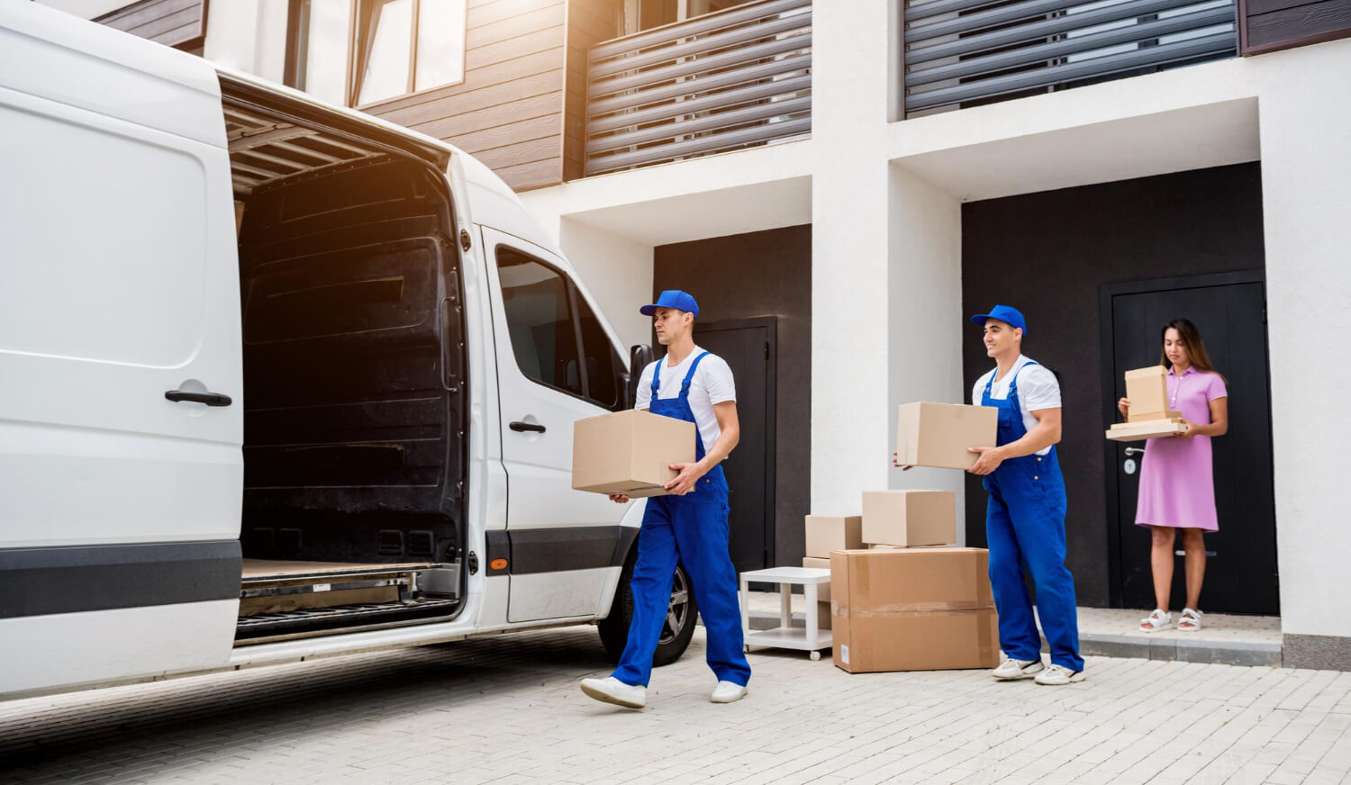 two movers and home ownder loading moving boxes into white moving van