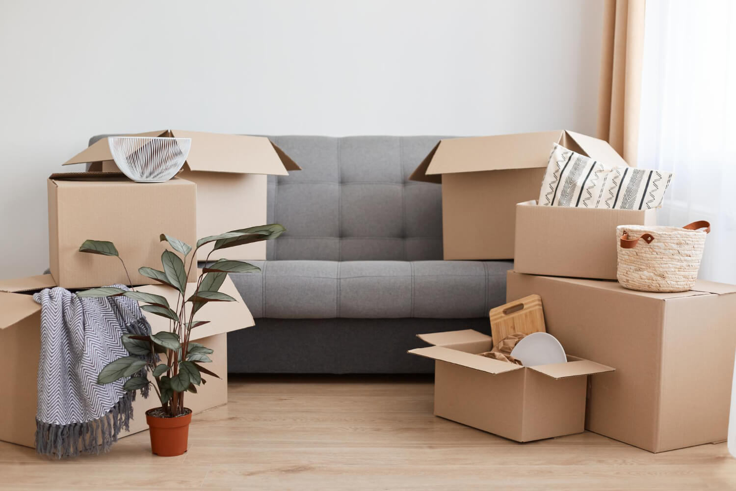 front view of living room with grey sofa and moving boxes on it and in front of it