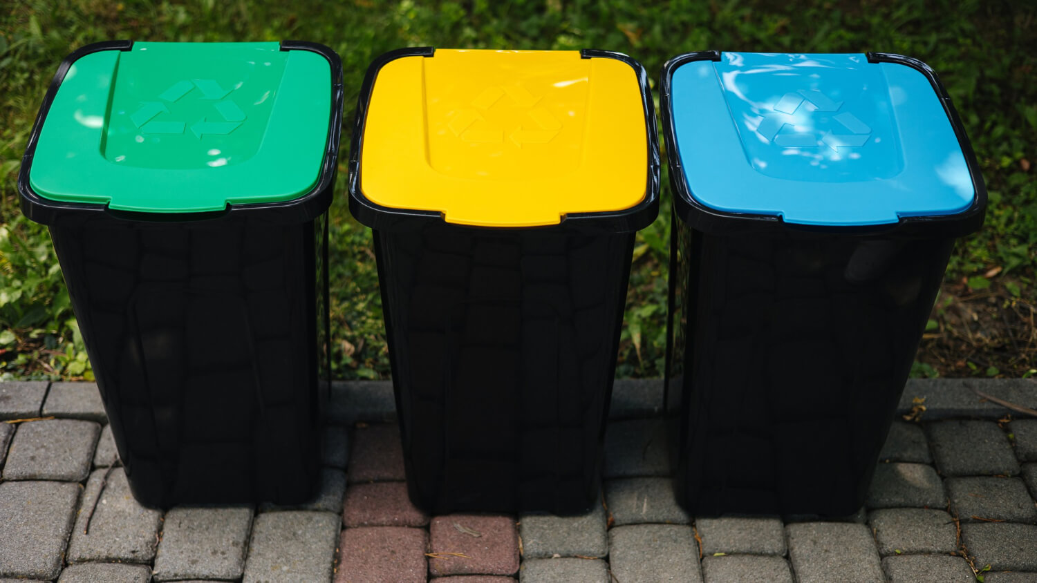 outdoors park with recycling bins with different colours green yellow blue