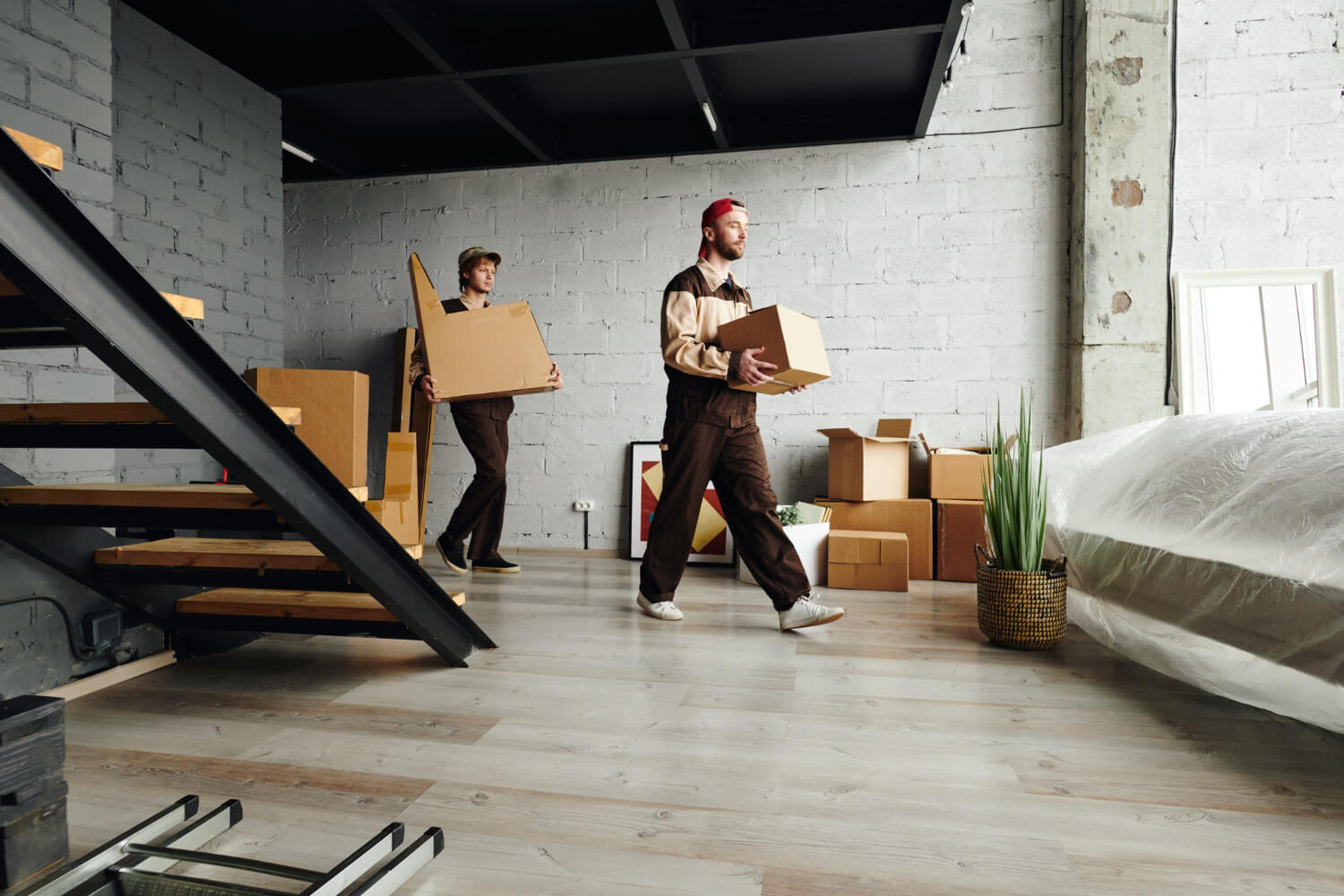 two movers holding moving boxes and placing them in new apartment