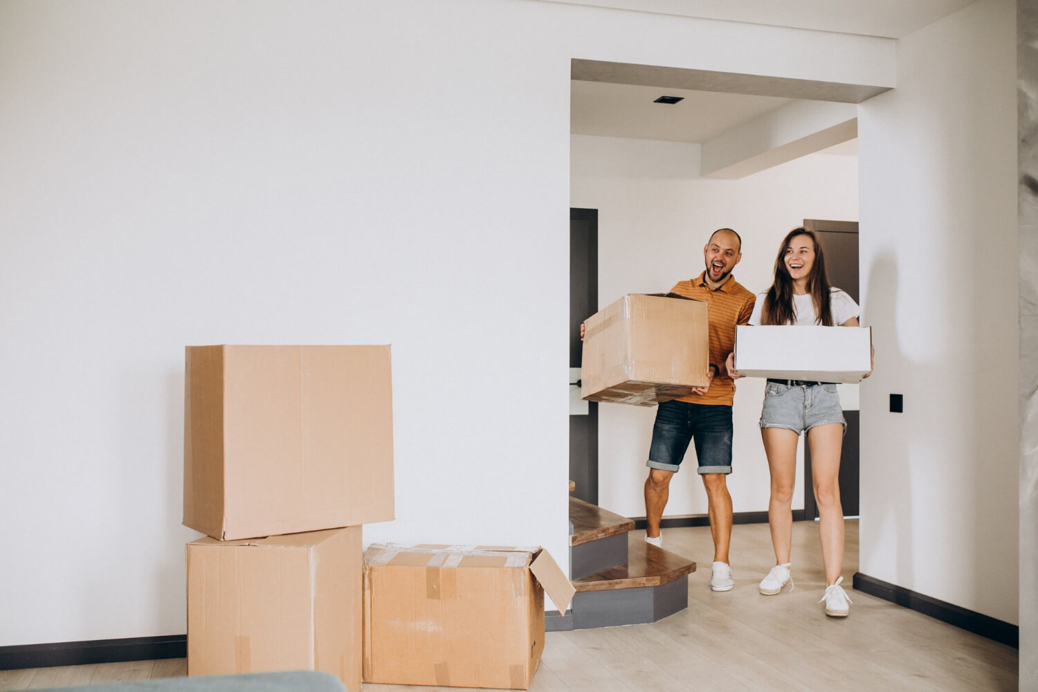 happy couple stepping in theis new home while holding moving boxes