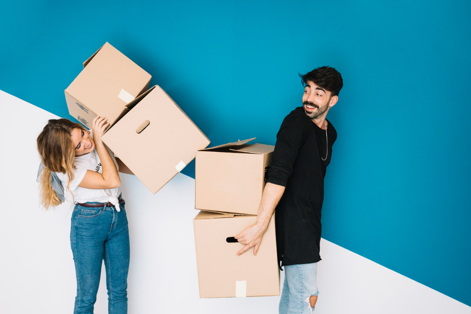 front view of man holding moving boxes on his back and woman putting more boxes on him for relocation