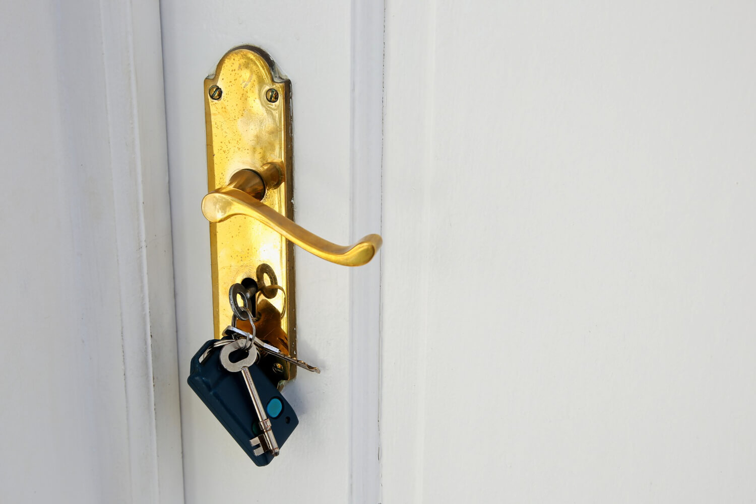 golden doorknob with keys on white door