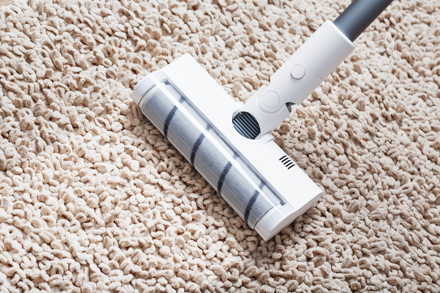 close up white turbo brush of a cordless vacuum cleaner cleans rug in house
