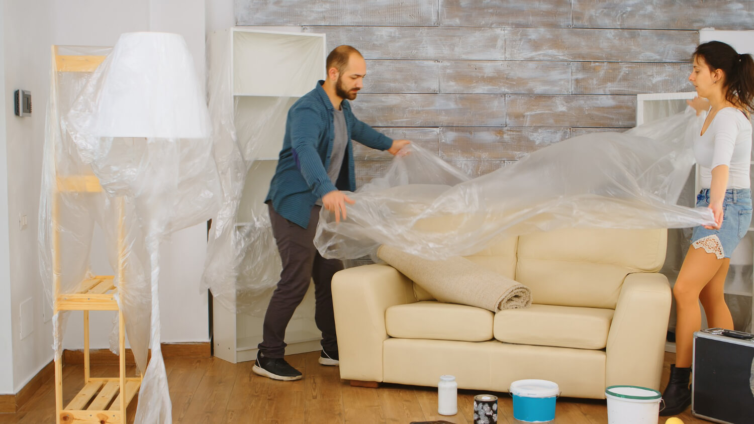 couple wrapping sofa with plastic foil protection for moving out