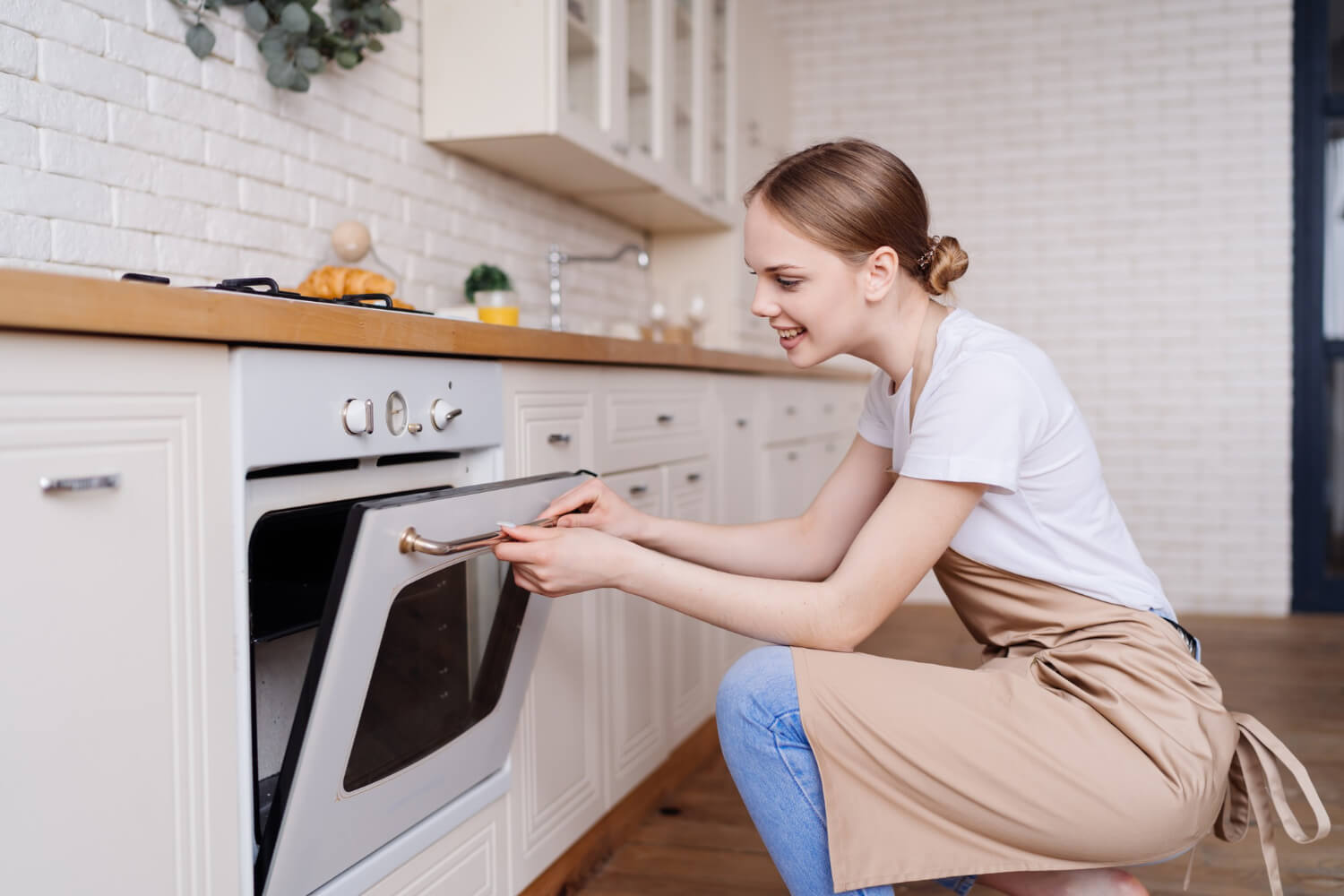 young woman in red shirt smiles whlie cleaning her single oven close up