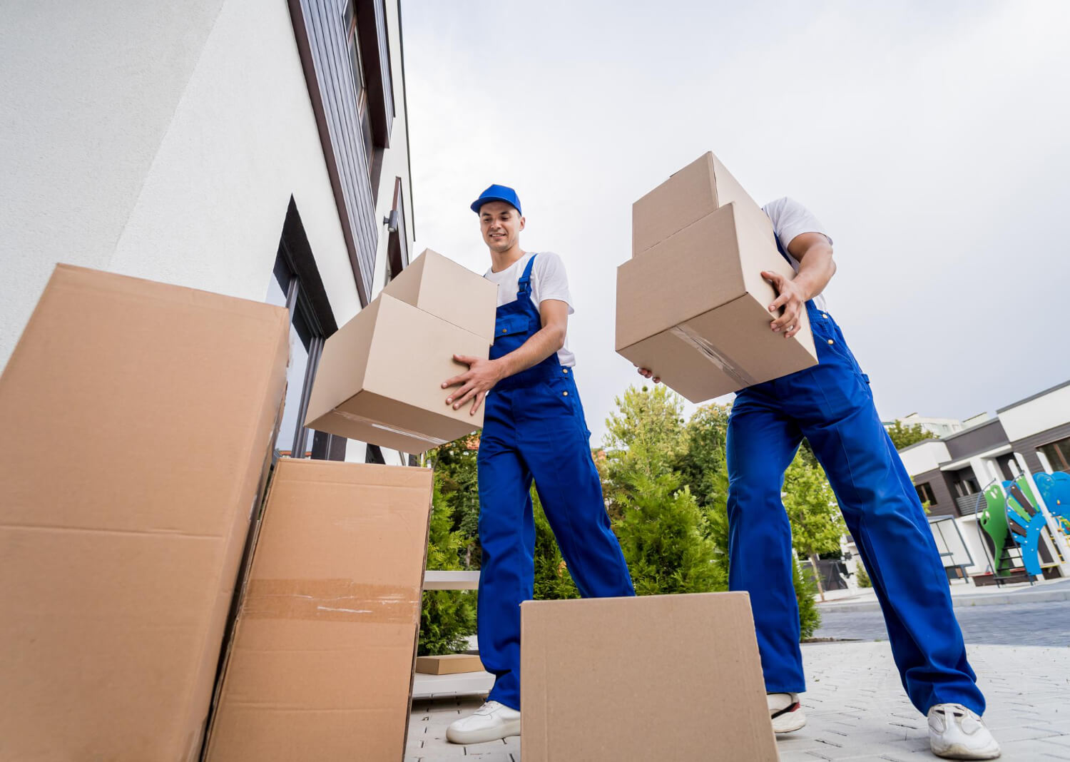 below view of two movers in uniform unloading moving boxes into customers new home