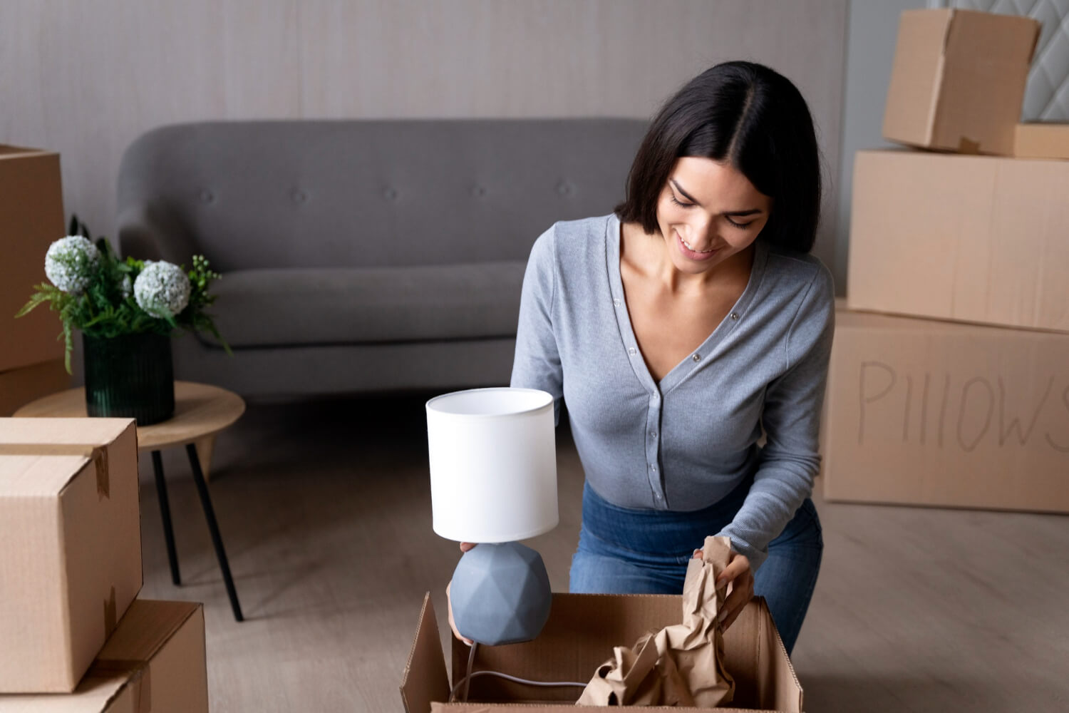 happy young woman packing her belongings in moving box for relocation