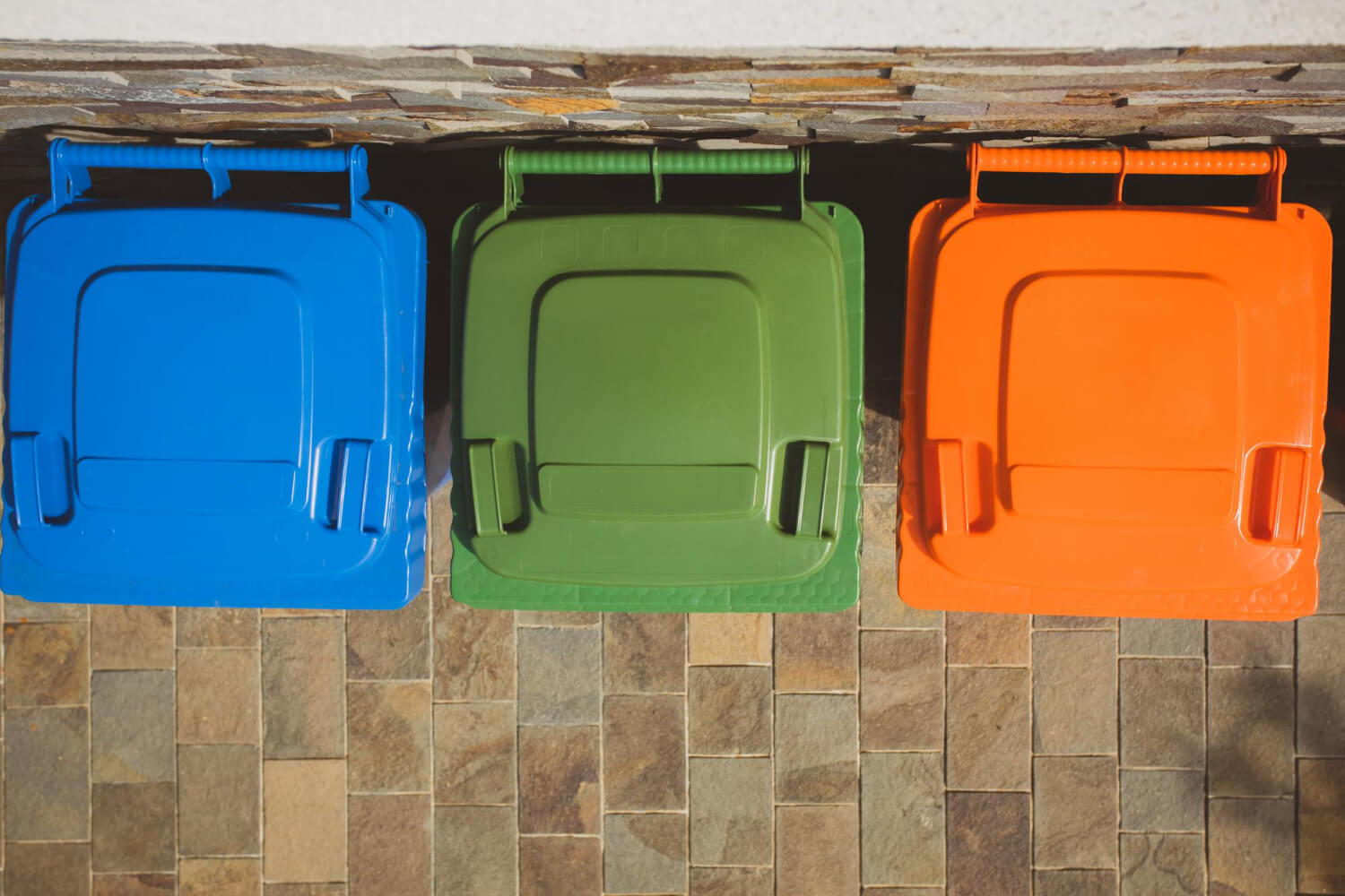 top view of three garbage containers with different colours blue yellow orange