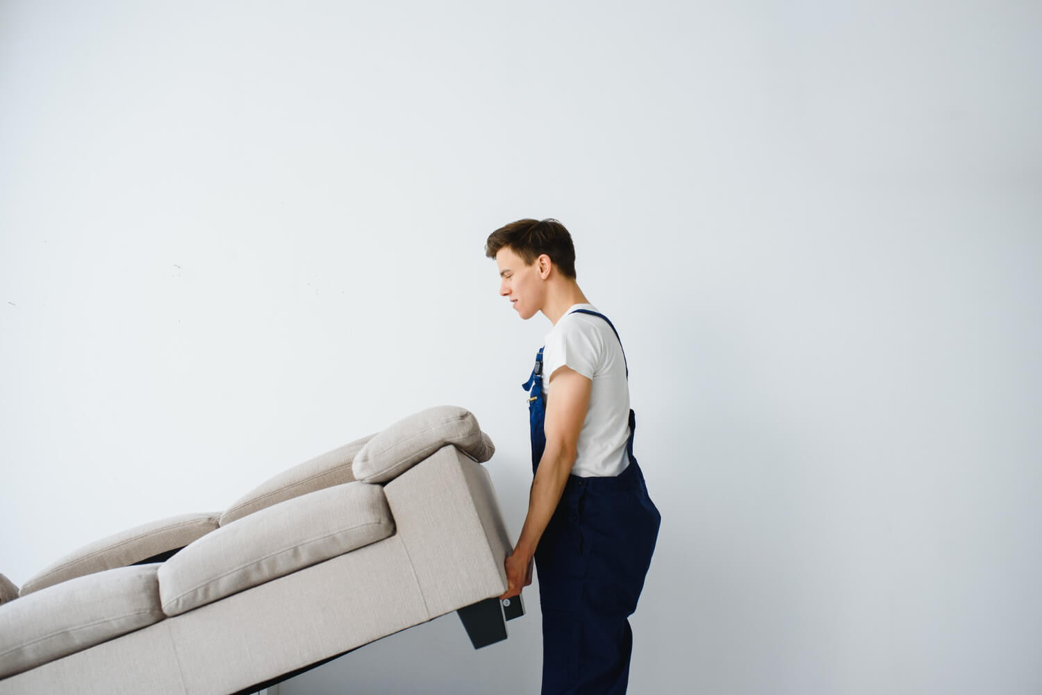 young mover overalls lifts up sofa for moving out