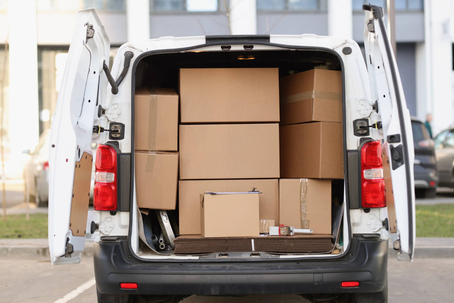 back view of white van with open doors full of moving boxes