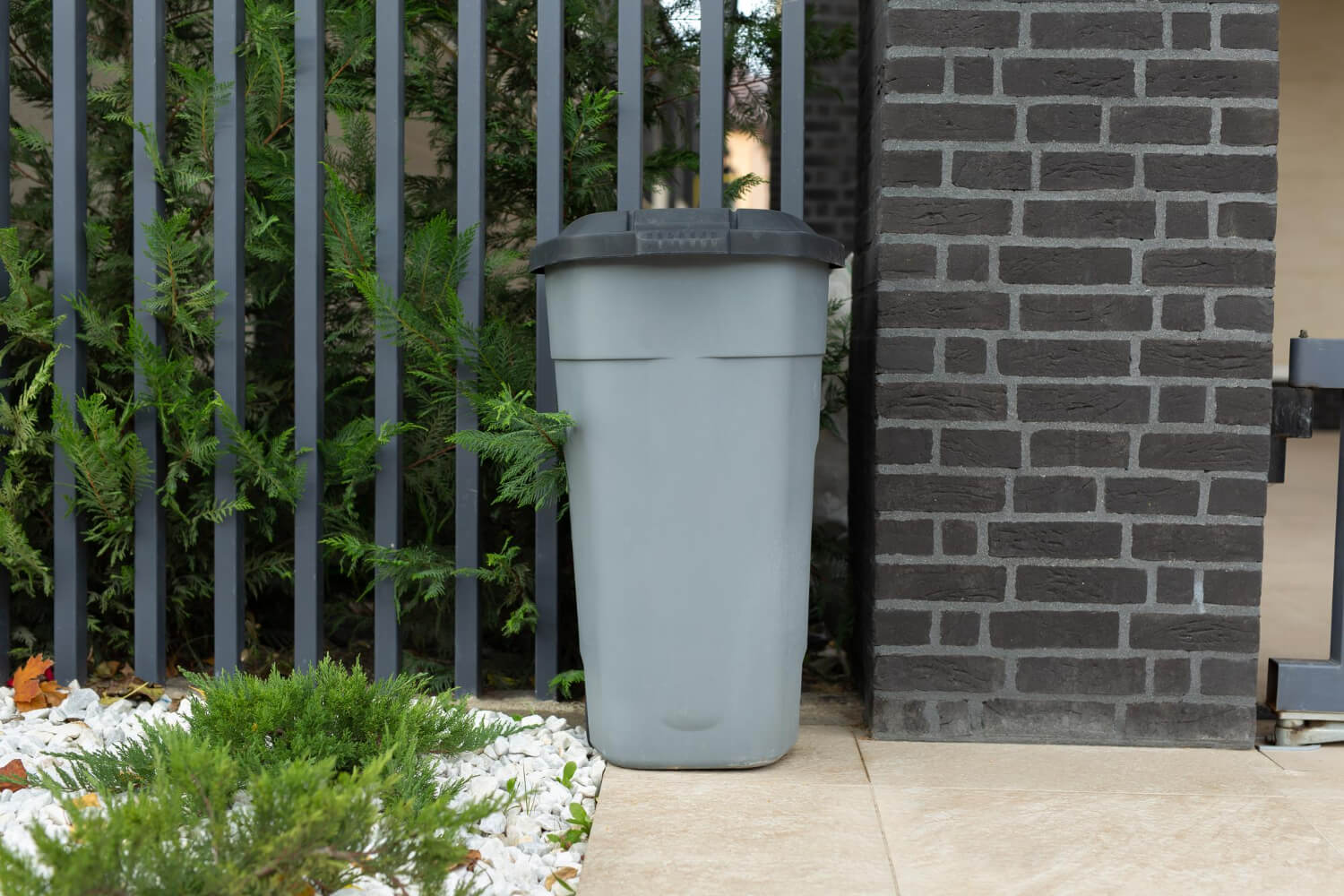 grey garbage bin in front of a street house