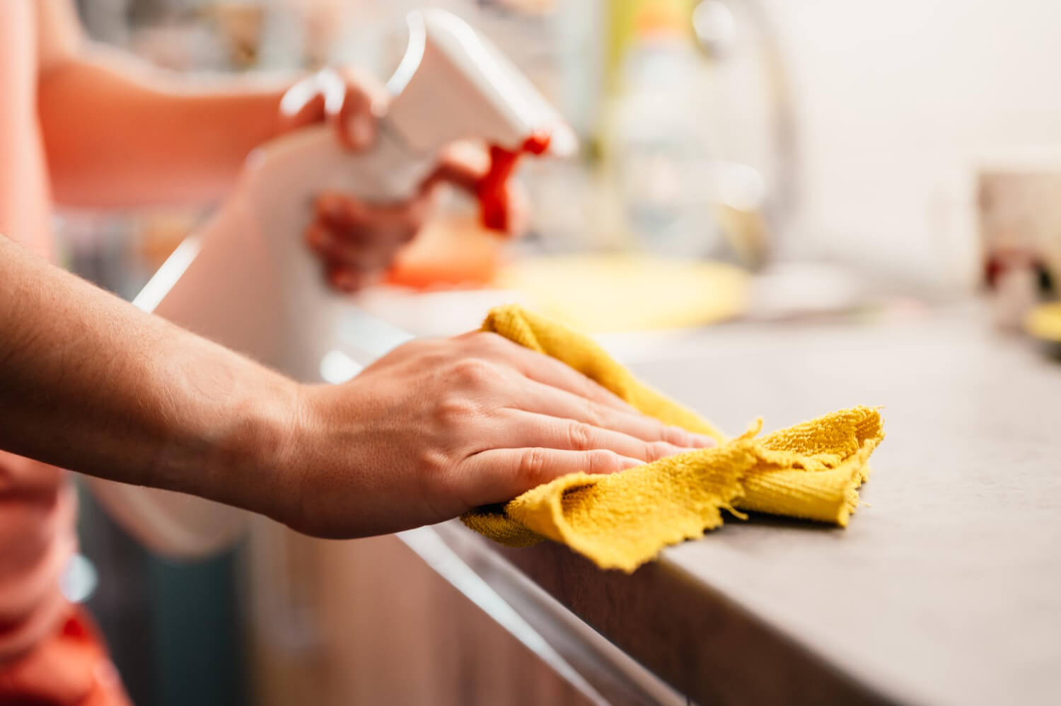 close up cropped female woman cleaning surface with yellow cloth and cleaning spray