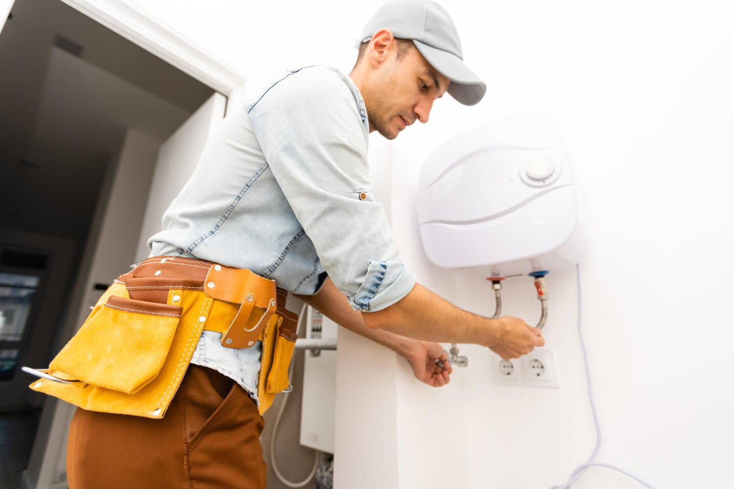 young plumber close up turning the knob of electric boiler
