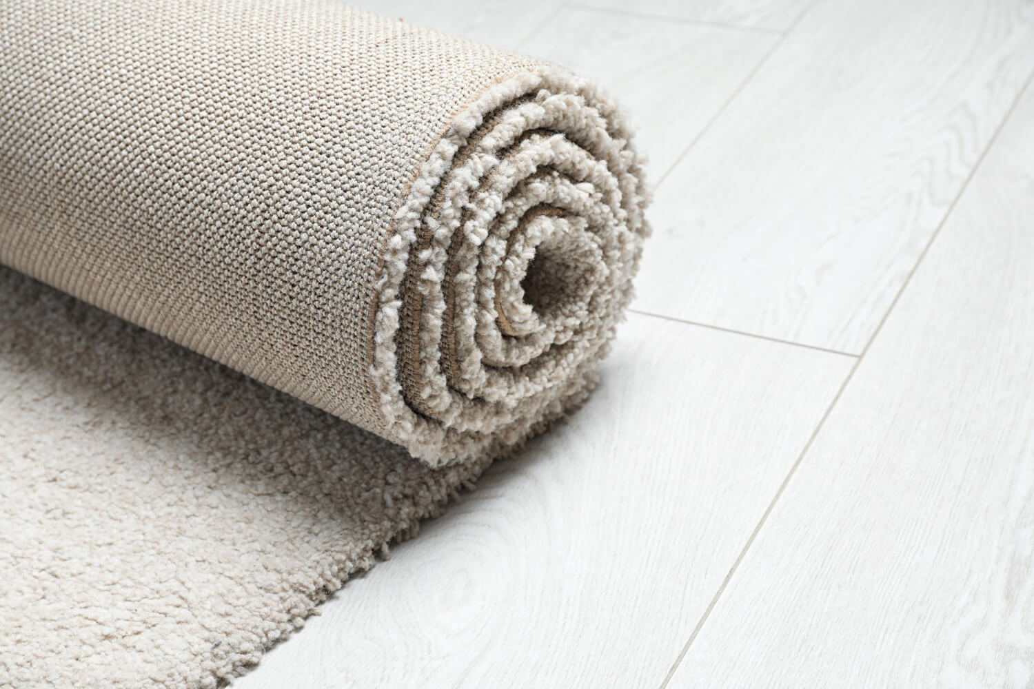 close up photo of rolled white rug on wooden floor