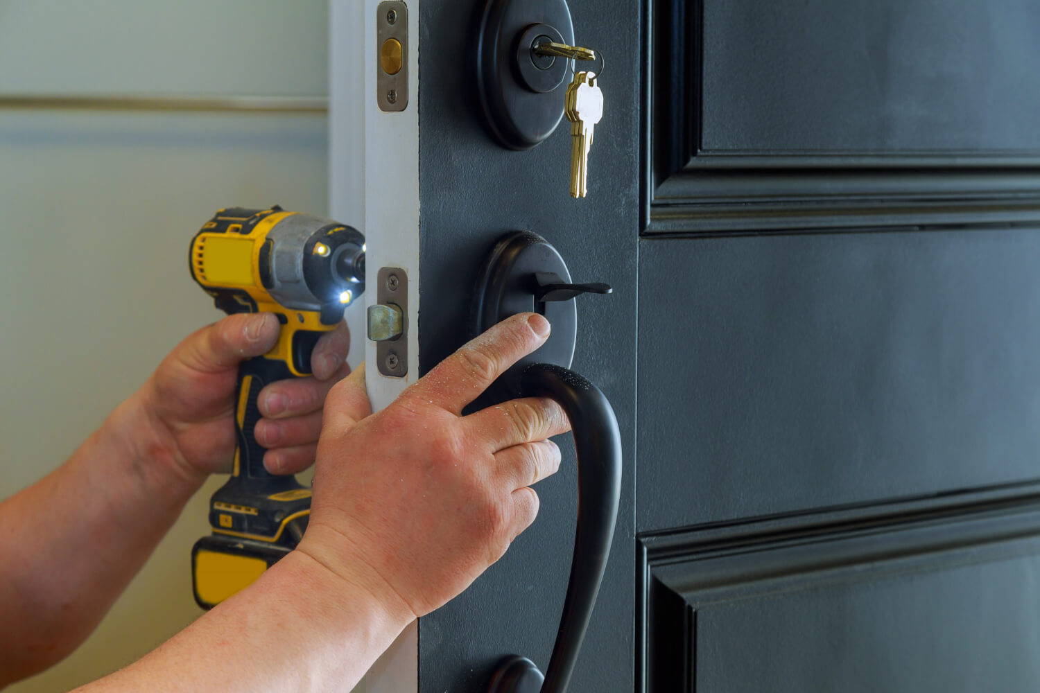 cropped handyman installs lock on exterior black door