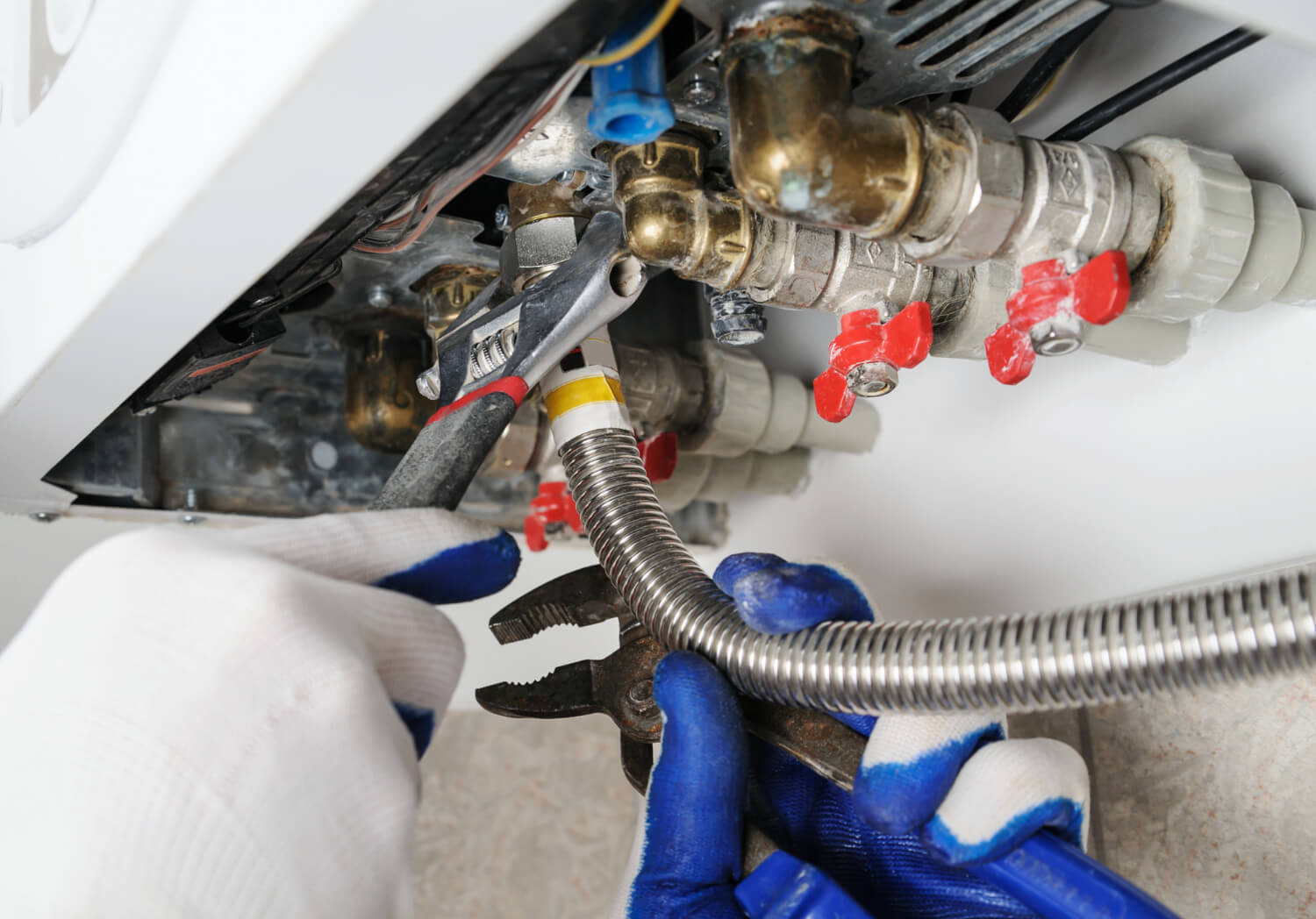 male plumbers hands below view trying to attach pipe on gas boiler