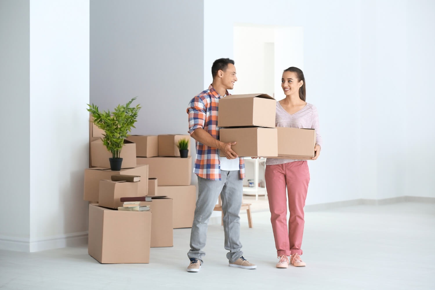 happu young couple moving in their new apartment holding boxes