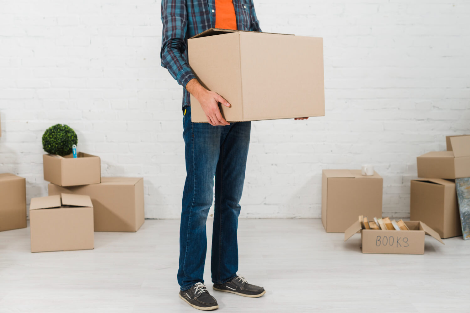 low section man holding cardboard box wth other moving boxes around him