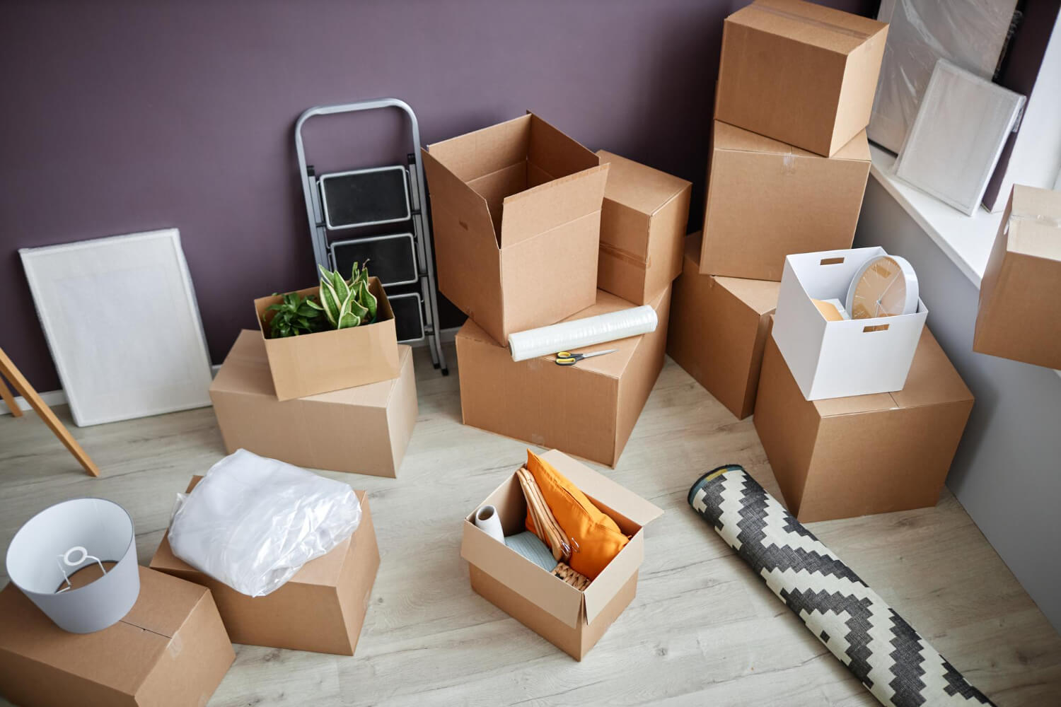 top view of living room with purple wall with moving boxes and wrapped carpet