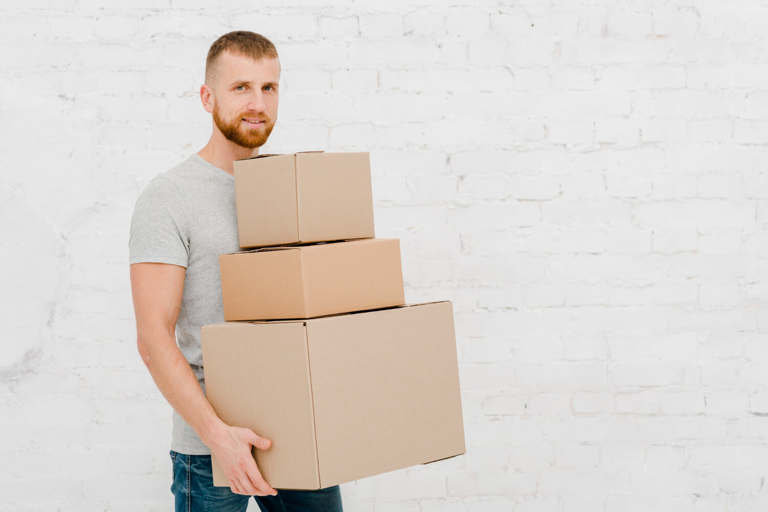 man smiling while holding staffed three carton moving boxes