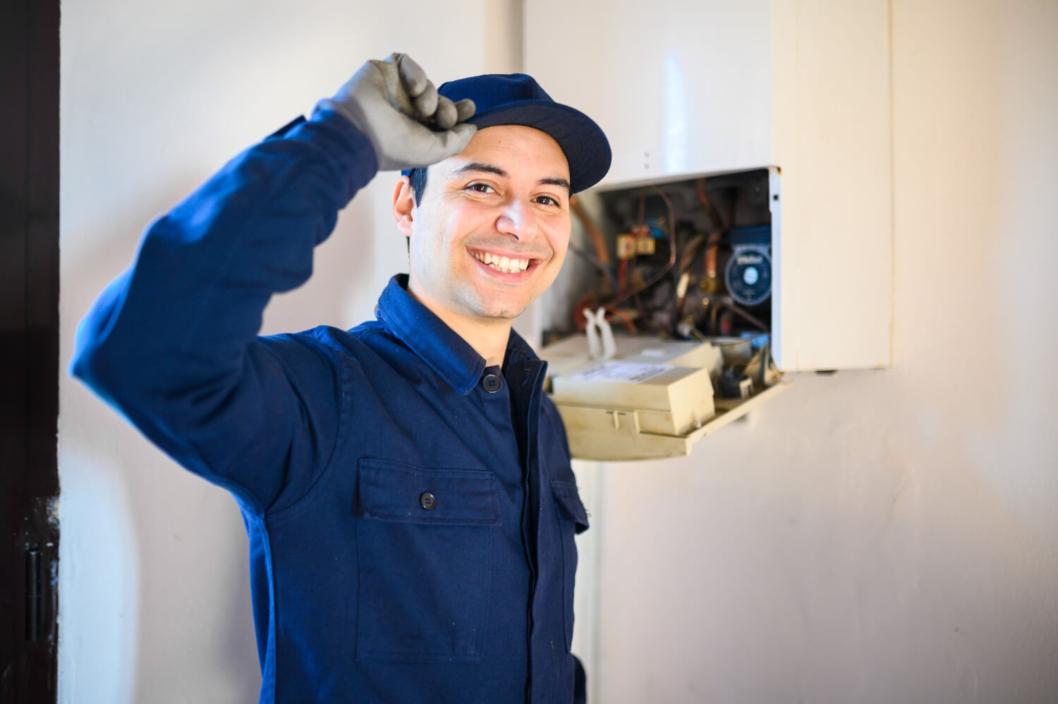 plumber smilling on camera with fixed boiler behind him