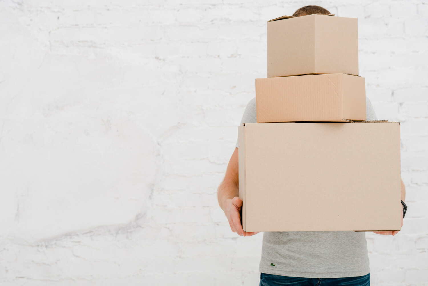 front view of a man holding three boxes and hiding behind them