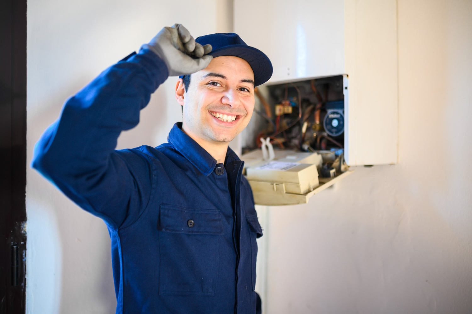 cropped plumber smiling on camera while fixing boiler behind him
